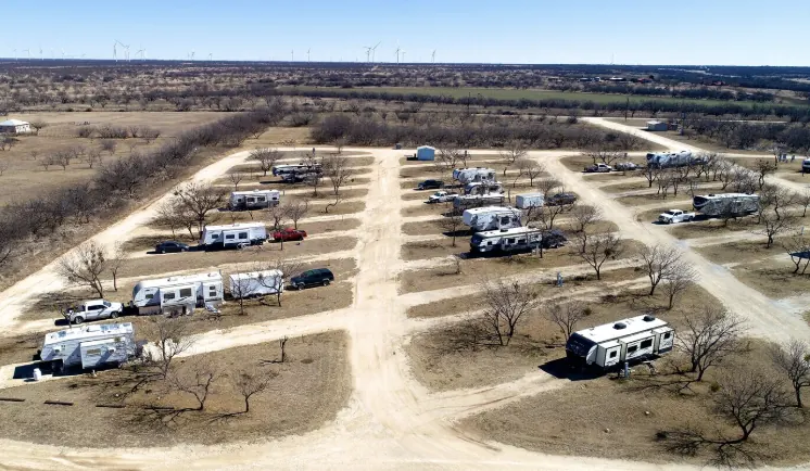 Aerial view of Buck Creek RV Park showing graveled site rows and wind turbines on the horizon