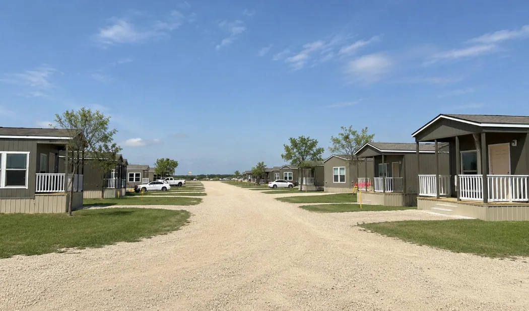A street of tiny homes with covered porches, front steps, and grass yards at a Buck Creek community