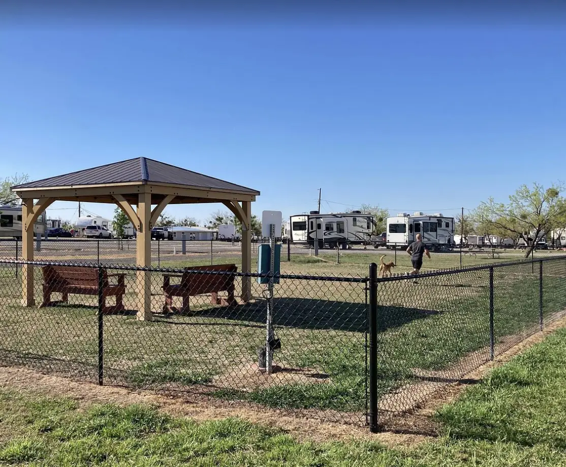 Fenced dog park at Tye RV Park with a shaded pavilion and benches